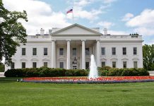 White building with fountain and flower garden front