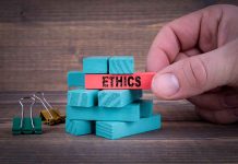 Hand holding red block labeled ethics above blue blocks.