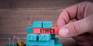 Hand holding red block labeled ethics above blue blocks.