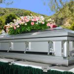 Silver casket with flowers at outdoor funeral