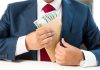 Person placing envelope with cash into suit pocket