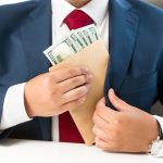 Person placing envelope with cash into suit pocket