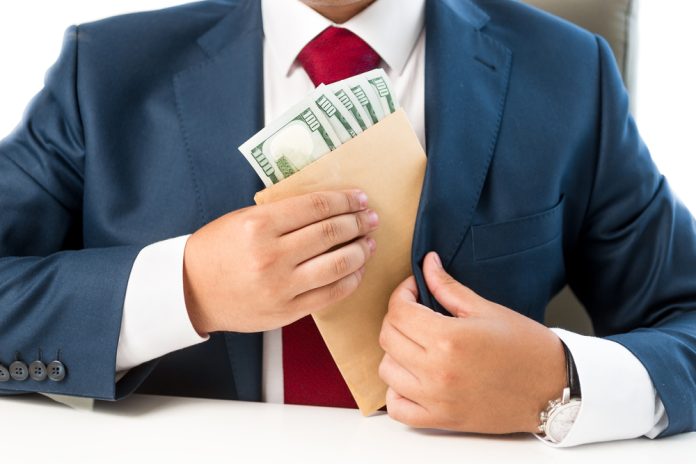 2419598047 featured image Person placing envelope with cash into suit pocket