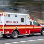 Red and white ambulance driving on street