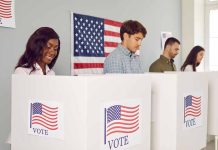 People voting in booths with American flag backdrop
