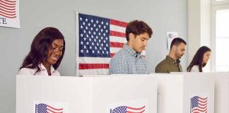 People voting in booths with American flag backdrop