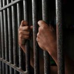 Hands gripping prison cell bars tightly
