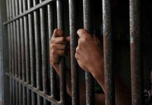 Hands gripping prison cell bars tightly