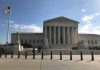 US Supreme Court Building with flag and people outside