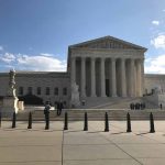 US Supreme Court Building with flag and people outside