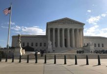 US Supreme Court Building with flag and people outside