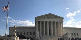 US Supreme Court Building with flag and people outside