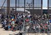Crowd of people sitting near border fence outdoors