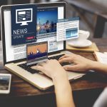 Person reading news websites on a laptop