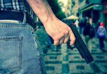 Person holding a gun in a crowded street
