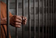 Hands gripping prison cell bars