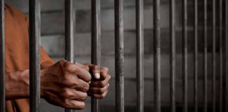 Hands gripping prison cell bars