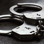 Close up of metal handcuffs on a dark surface