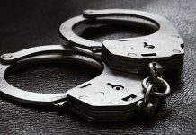 Close up of metal handcuffs on a dark surface