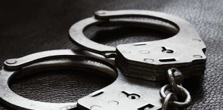 Close up of metal handcuffs on a dark surface