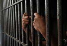 Hands gripping prison cell bars tightly