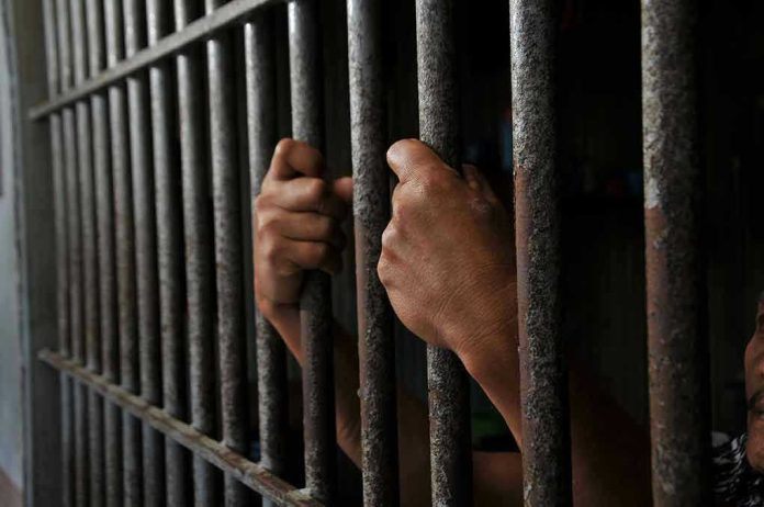 2452368639 Hands gripping prison cell bars tightly