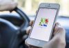 A person holding a smartphone displaying the Google Maps app while driving