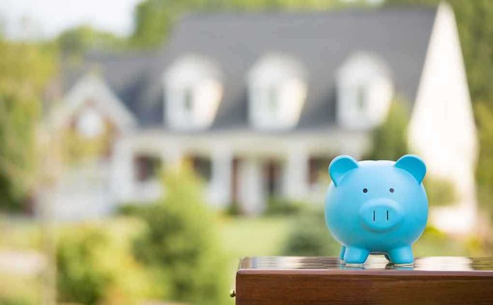 A blue piggy bank in front of a blurred house and greenery