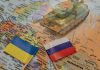 Toy tank on map with Ukraine and Russia flags.