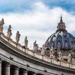 St. Peter's Basilica dome with statues and clouds.