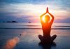 Person meditating on the beach during sunset
