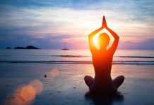 Person meditating on the beach during sunset