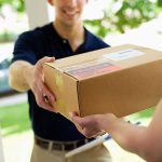 A delivery person handing a package to a customer at their doorstep