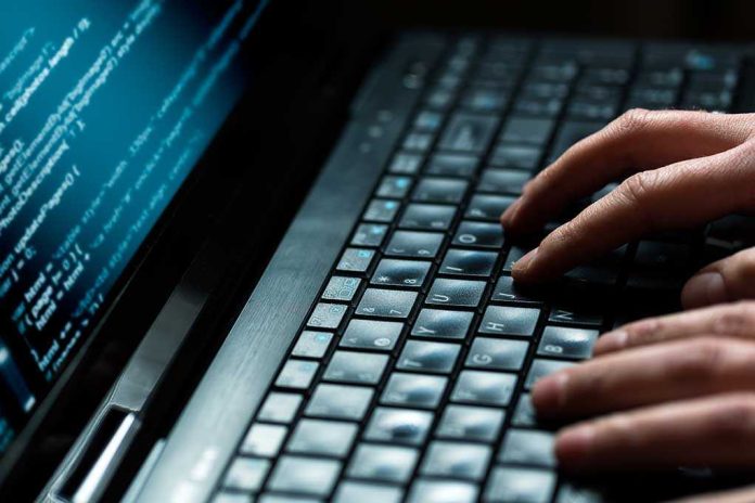 Close-up of hands typing on a laptop keyboard with code displayed on the screen