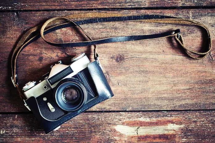 shutterstock_197574791.jpg A vintage camera resting on a wooden surface with a leather strap