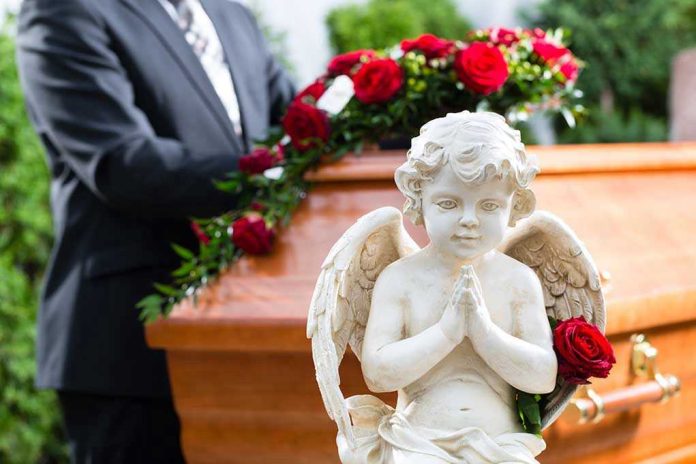 Statue of angel in front of coffin with roses.
