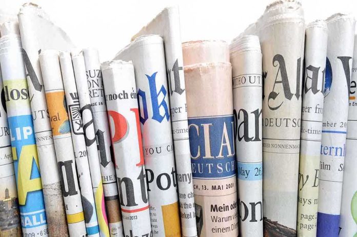 shutterstock_179149739.jpg A collection of rolled newspapers displaying various headlines and designs