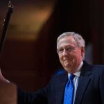 A man in a suit holding a gavel at a podium