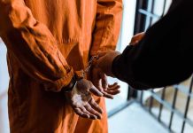 Shocking Prison Blunder – Convicted Offender Freed! Handcuffed person in orange jumpsuit being escorted.