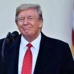 $10 Billion Showdown – Toyota BACKS Trump! Man in suit and tie speaking at podium.