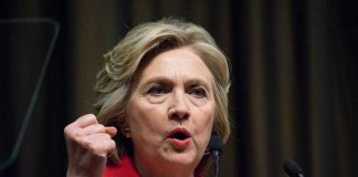 Person speaking passionately at a podium, wearing red jacket.