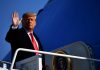 Trump ADMITS Strategy “Not Sustainable” — Refuses Retreat A political figure waving while standing on the steps of an aircraft