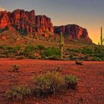 Desert landscape featuring mountains and cacti at sunset