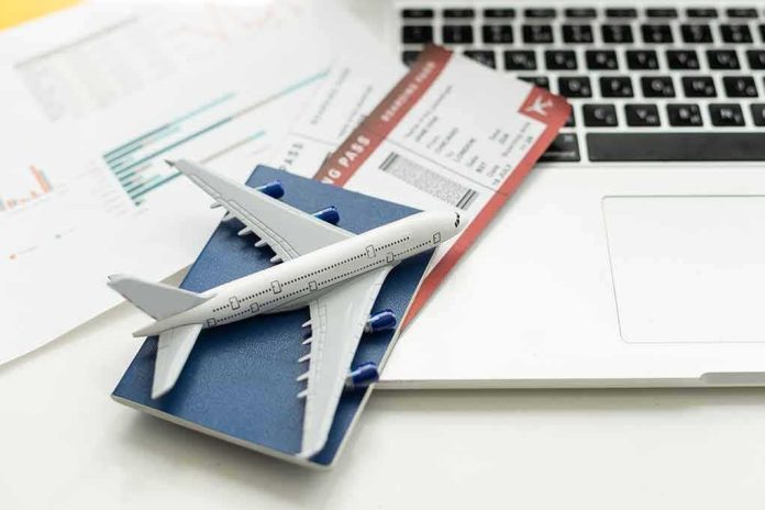 shutterstock_2336014405.jpg A model airplane on a blue passport next to a laptop and boarding pass