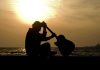 Silhouette of a guitarist sitting by the ocean during sunset