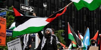 Palestine Activists Storm Store – Black Friday Chaos Erupts Protesters with flags and signs, one holding a megaphone.