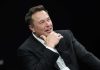Musk’s Package REINSTATED: Trillionaire Pathway Set Man in suit smiling, resting chin on hand.