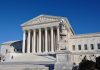 The Supreme Court building with large columns and a clear blue sky