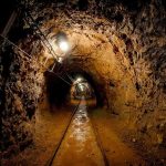 Lost Coal Miners FOUND – Daring Rescue Underway Dimly lit underground tunnel with rail tracks and rocky walls