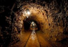 Lost Coal Miners FOUND – Daring Rescue Underway Dimly lit underground tunnel with rail tracks and rocky walls